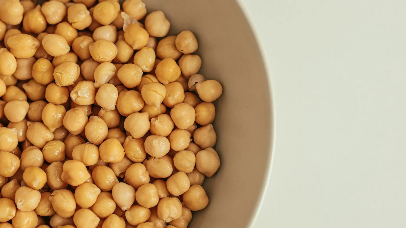 Tazón beige con garbanzos cocidos visto desde arriba, una de las leguminosas que aportan proteína vegetal en la cocina de casa
